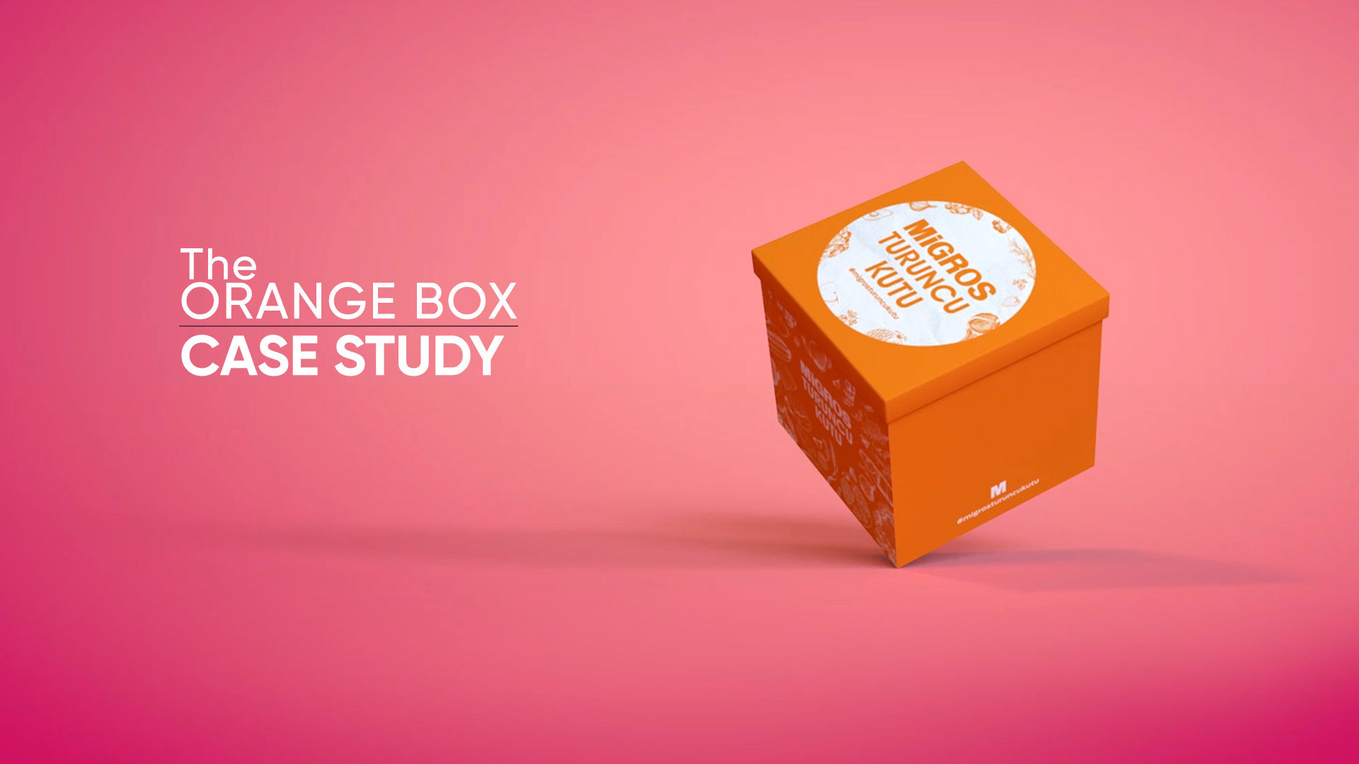 The Orange Box 3D animasyonundan pembe zemin üzerinde havada duran turuncu Migros kutusu